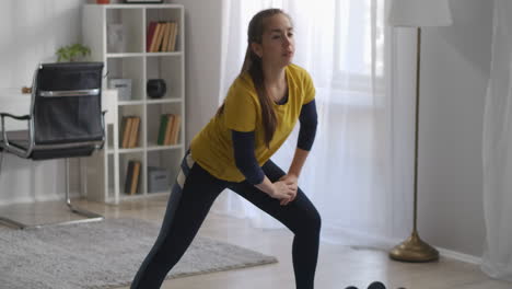 crouching-in-living-room-during-morning-workout-teenager-girl-is-doing-sport-in-home-during-self-isolation-at-pandemic-sporty-and-health-lifestyle